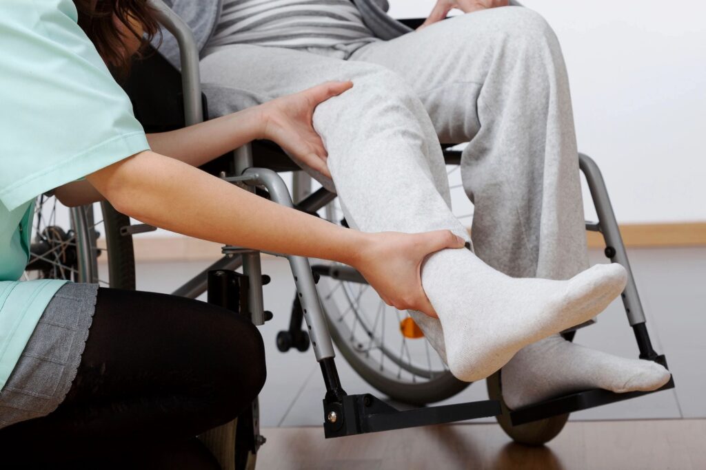 Patient in a wheelchair having his foot examine by a healthcare provider.